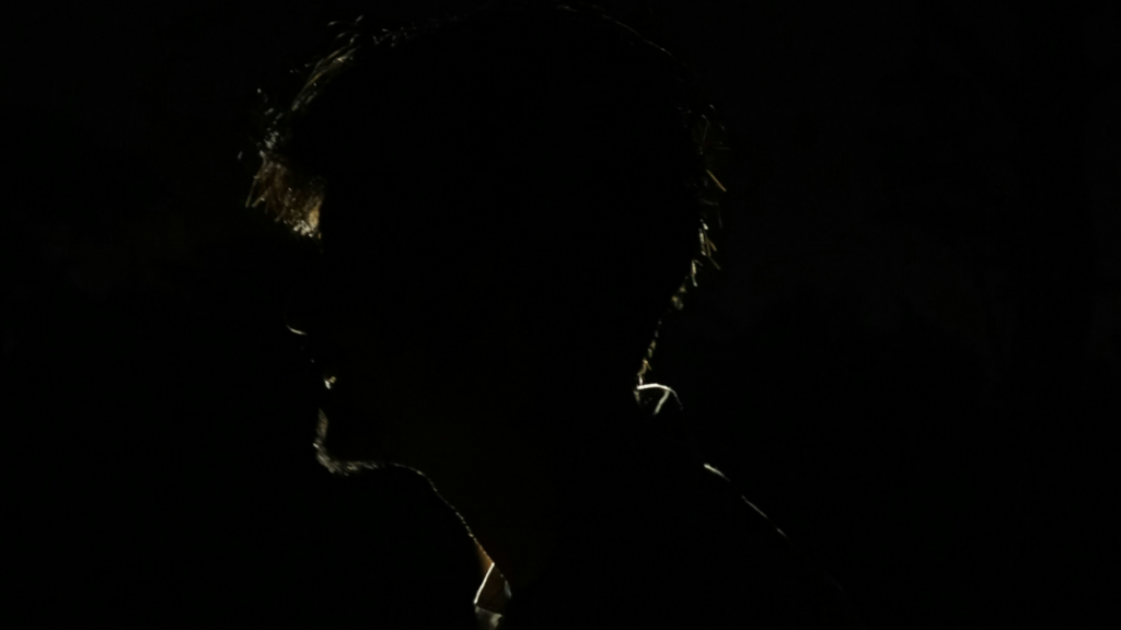 Mroczny profil mężczyzny w silnym kontraście, ukazujący jedynie zarys twarzy na czarnym tle, symbolizujący tajemnicę i ukrytą prawdę.