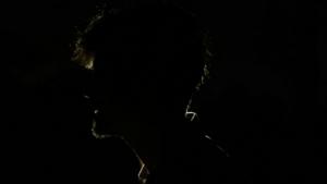 Mroczny profil mężczyzny w silnym kontraście, ukazujący jedynie zarys twarzy na czarnym tle, symbolizujący tajemnicę i ukrytą prawdę.